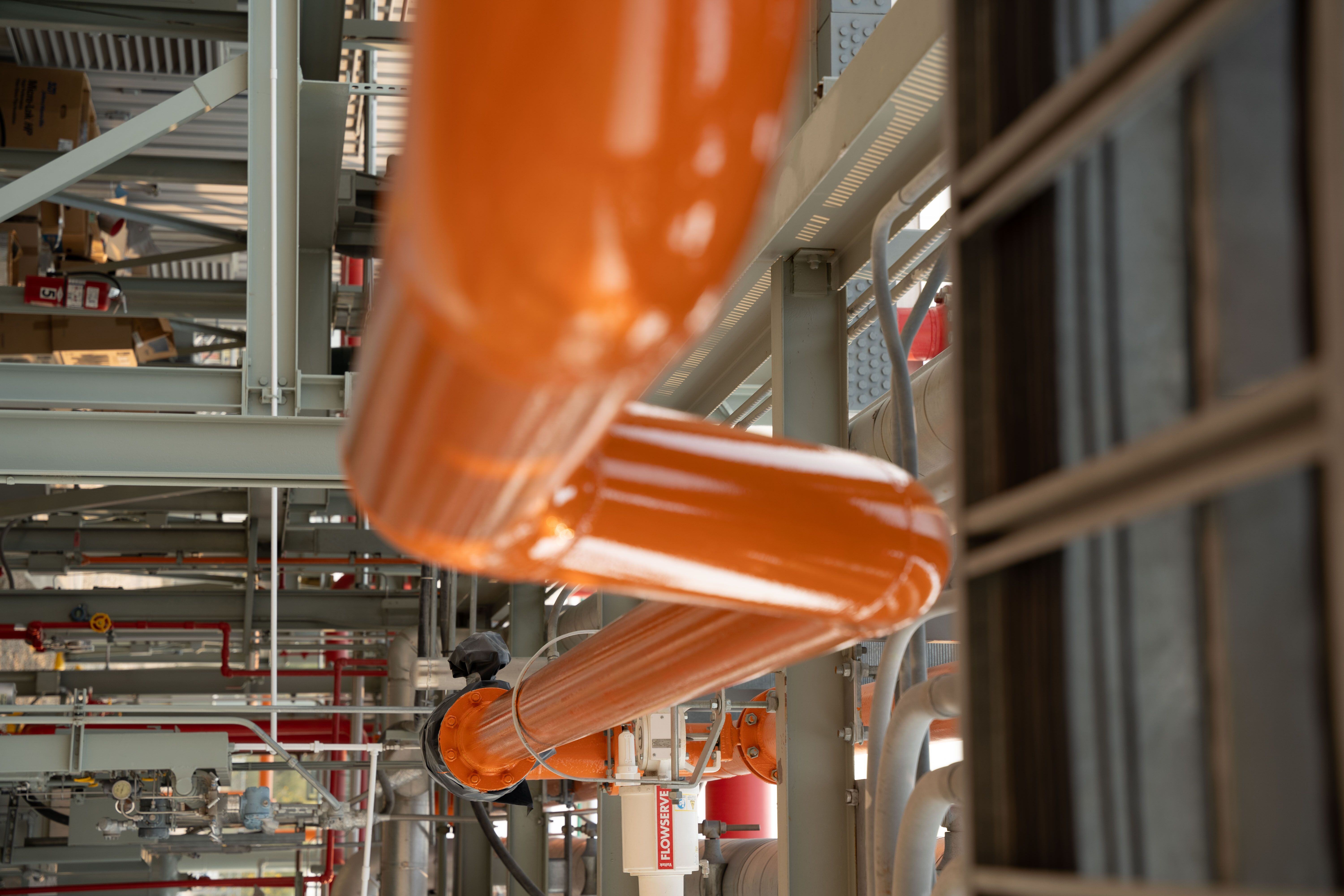 bright orange industrial pipe coating inside a production facility