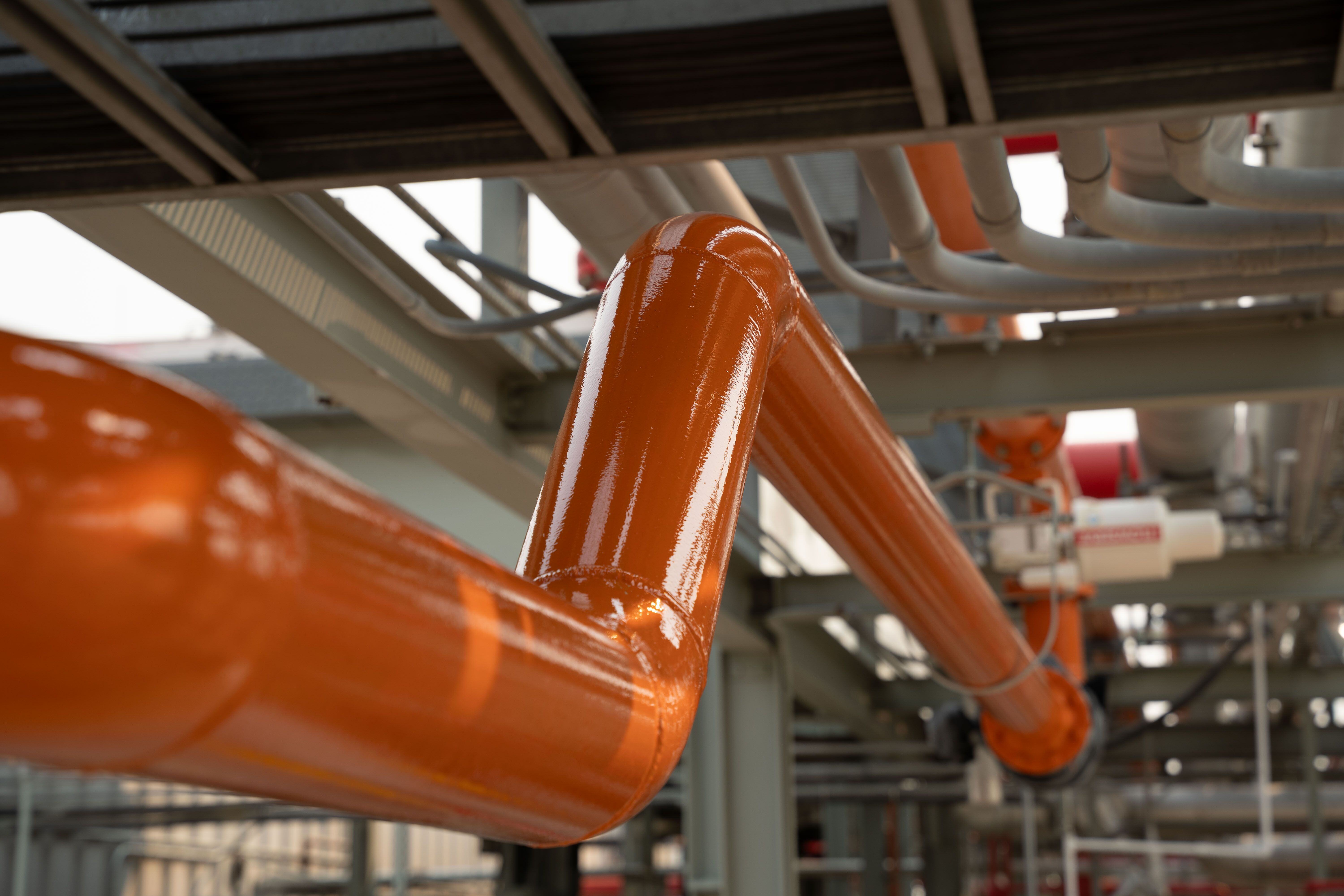 freshly coated industrial piping with bright orange coating