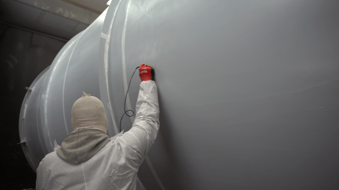 crew member testing an industrial tank coating mid-project to ensure proper thickness and curing of the tank coating