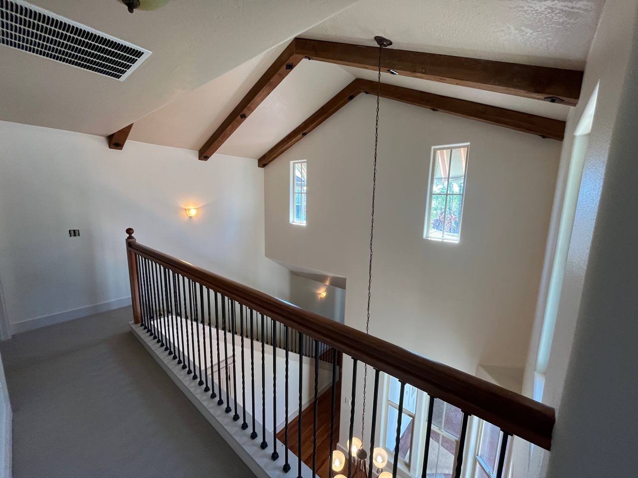 residential painting job of the interior of a home in Eagle, Idaho. Wood beams on a vaulted ceiling of a two-story living space