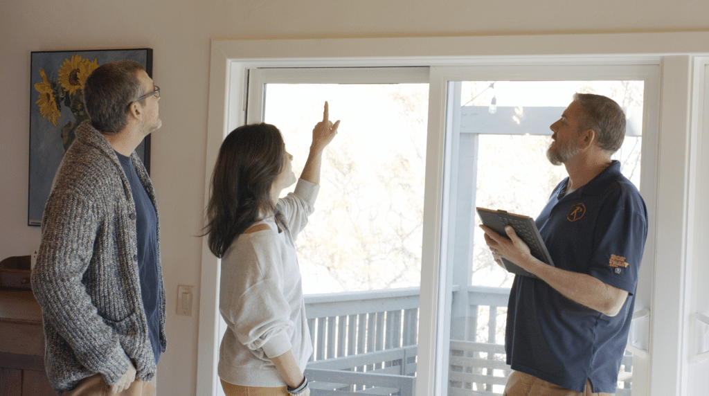 man and woman standing by the door, consulting a contractor holding a tablet inside the house
